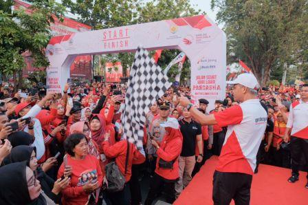 Gubernur Jawa Tengah, Ganjar Pranowo, mengibaskan bendera start pada acara jalan sehat di Kabupaten Grobogan, Jumat (16/6/2023)